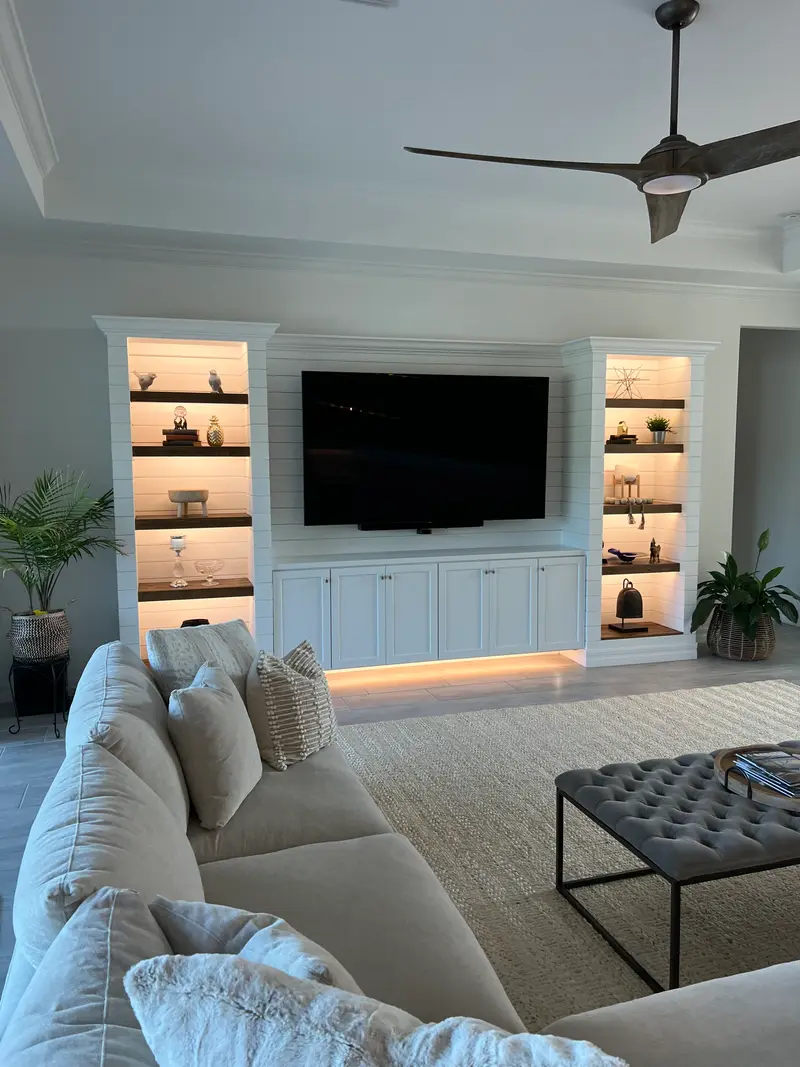 White shiplap built-ins with backlit shelving, lower cabinets and a wall-mounted TV