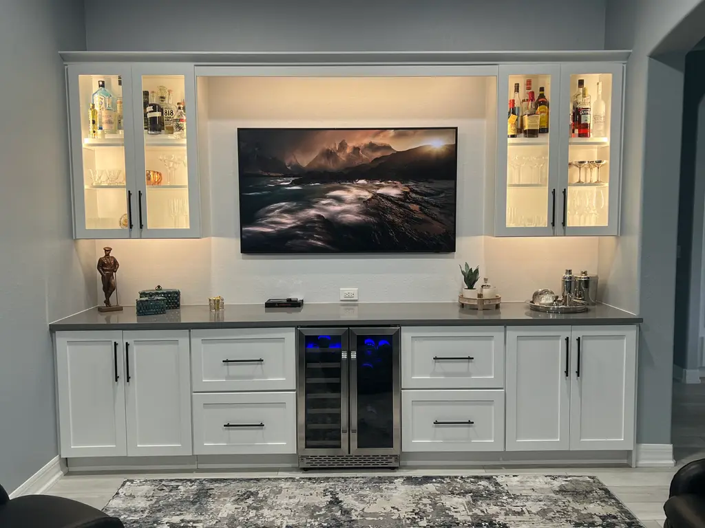White bar wall with lit glass-front cabinets, a beverage cooler and a quartz counter
