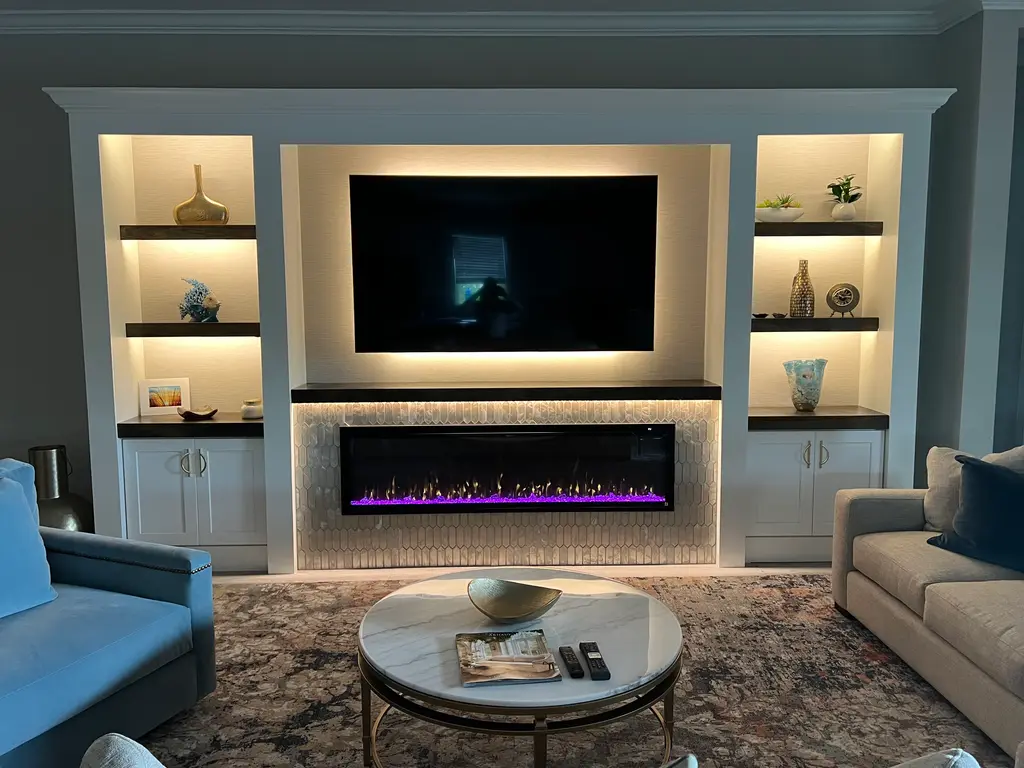 Painted built-in wall with backlit shelves, a glowing linear fireplace and a TV niche