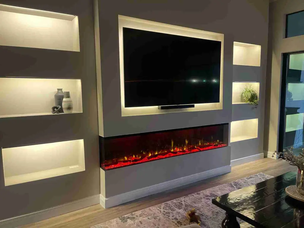 Floating feature wall with lit display niches and a wide electric fireplace with red flame setting