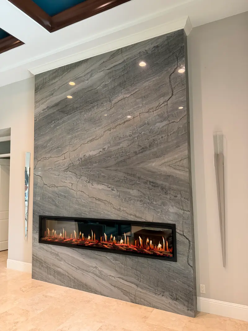 Front view of a chevron-veined granite wall with a flush linear electric fireplace