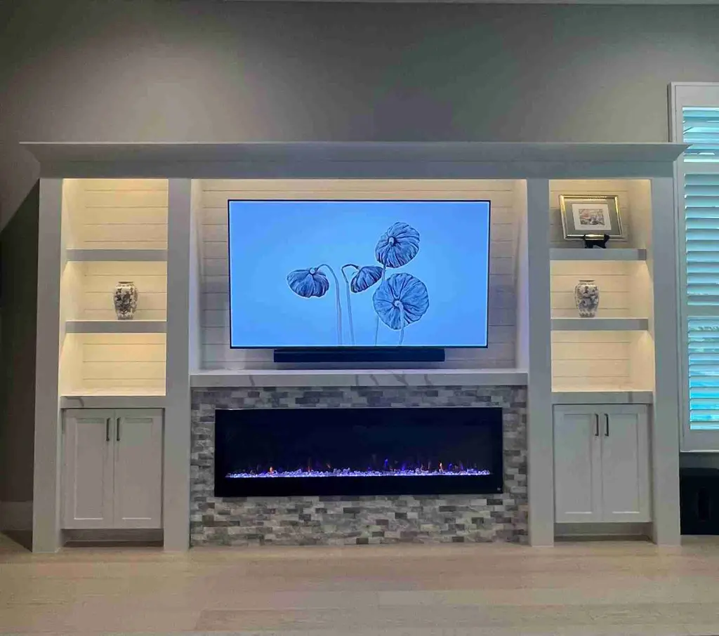 White built-in with lit shelves, cabinets and a mosaic-tile surround around a linear fireplace