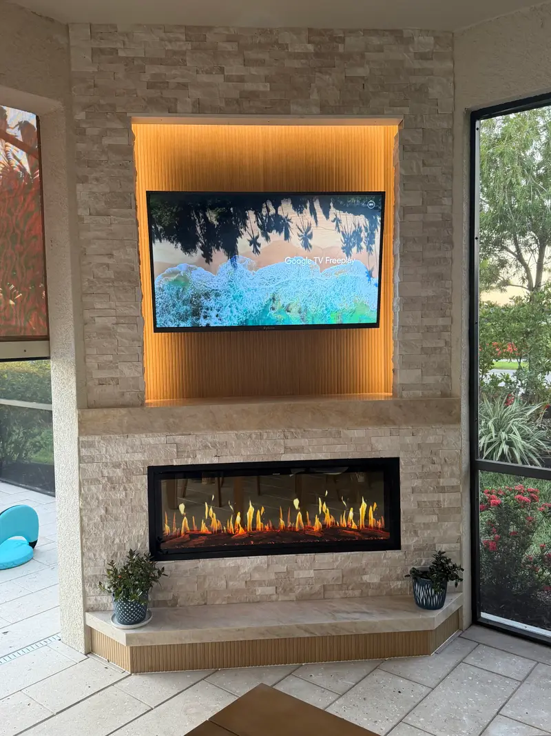 Stacked-stone electric fireplace with a lit wood niche and TV on a screened lanai
