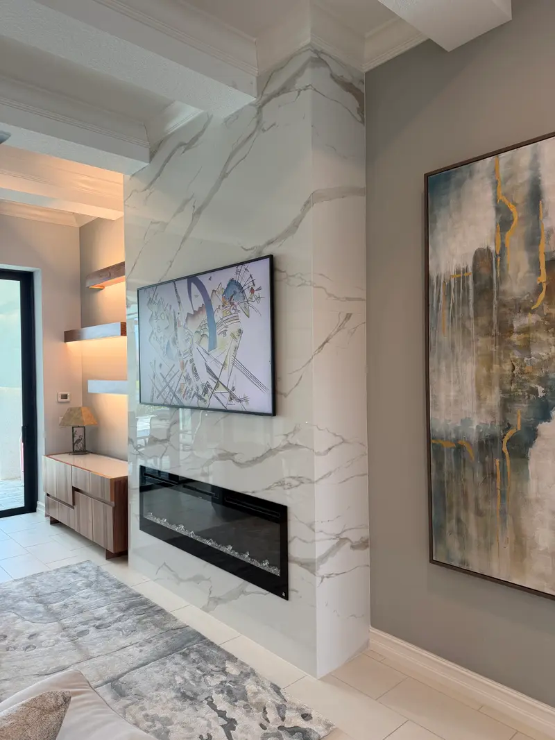 Floor-to-ceiling marble-look column with a linear electric fireplace and art-framed TV