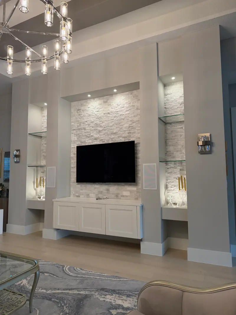 Bright white architectural niche wall with a stacked-stone inset, lit glass shelving and a floating cabinet
