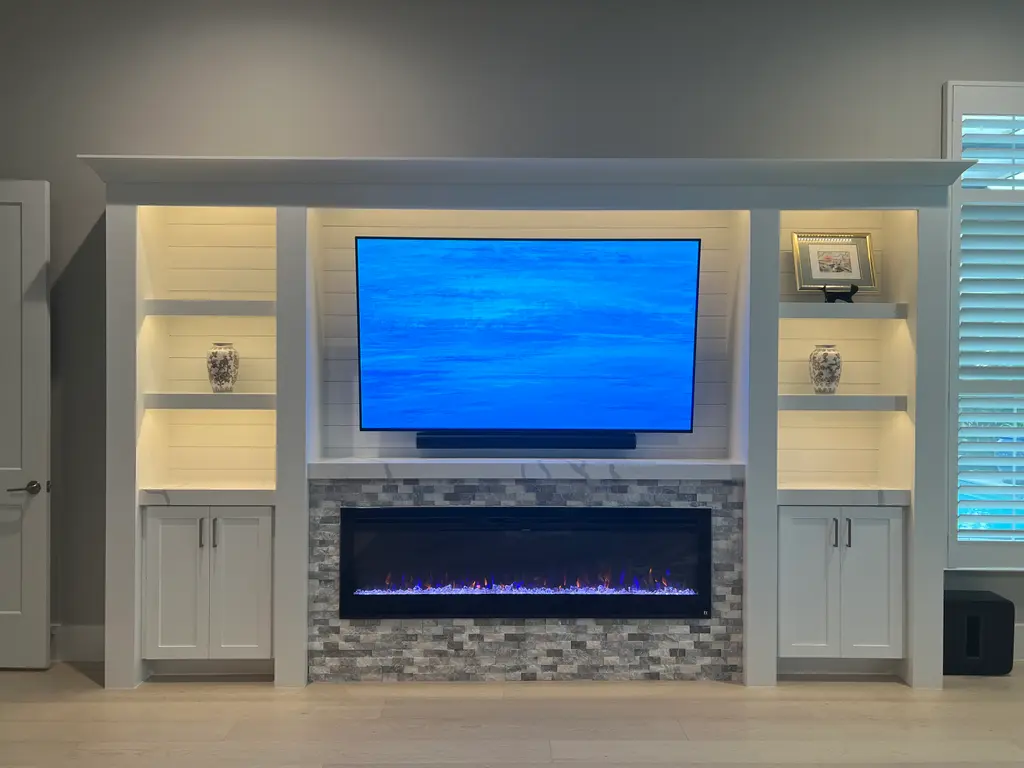 White built-in with shiplap, lit display shelves and a tile-surround linear electric fireplace