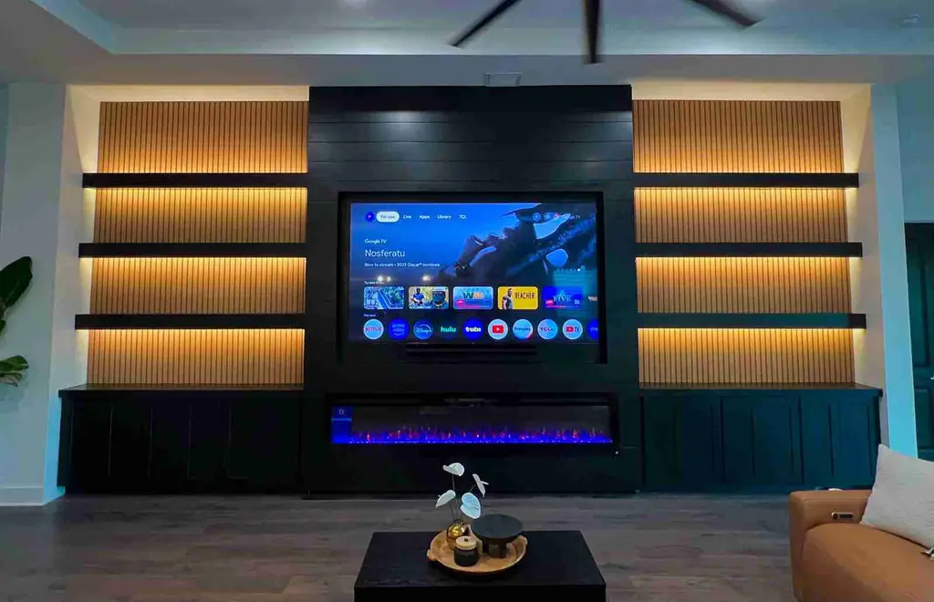 Wide view of a black shiplap media wall with backlit slat shelves and linear electric fireplace