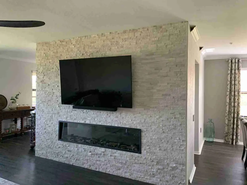 Freestanding split-face stone wall with a recessed linear electric fireplace