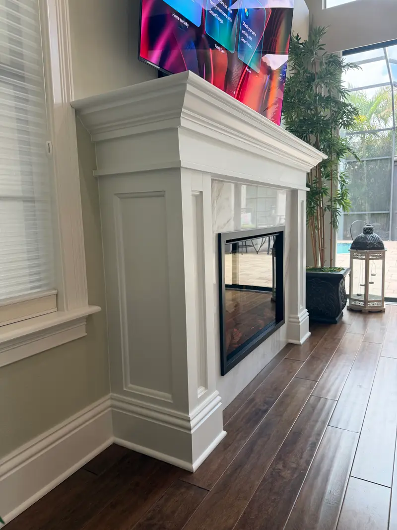 Side view of a traditional white mantel with a marble surround and an electric fireplace