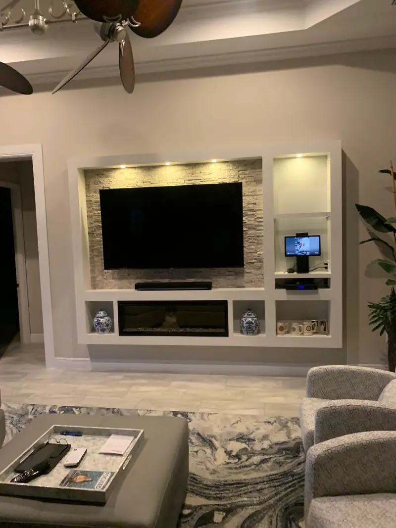 White built-in with a stone-inset TV wall, open shelving and a linear electric fireplace