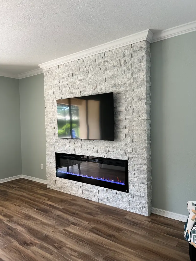 White stacked-stone feature wall with a wall-mounted TV and a linear electric fireplace